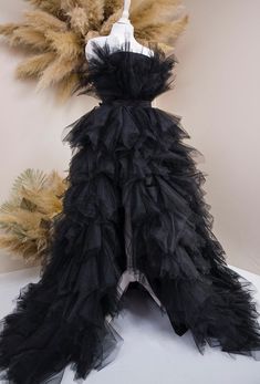 a black dress with feathers on display in front of a white wall and tan background