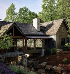 this is an artist's rendering of a house in the woods with stone and wood accents