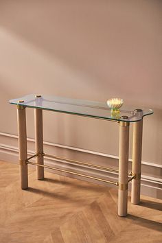 a glass table sitting on top of a hard wood floor next to a white wall