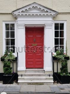 a red front door with potted plants on either side