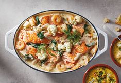 two bowls of soup with shrimp, cauliflower and carrots on the side