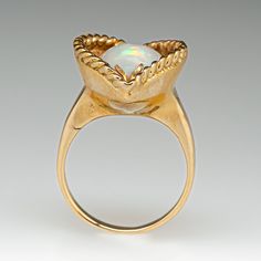 This pretty ring is accented with one (1) oval cabochon cut natural semi-crystal opal that is recessed into the gallery and set with two-chevron shaped prongs. The lip of the gallery is bordered with a rope detail. The ring measures 20.3mm at the top, rises 9.5mm above the finger, tapering to 2.0mm wide and 0.8mm thick at the base of the shank. The ring is currently a size 4.5. Pretty Ring, Crystal Opal, Pretty Rings, Opal Ring, Opal Crystal, One 1, Oval Cabochon, Opal Rings, The Gallery