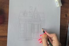 a person is drawing a house on paper