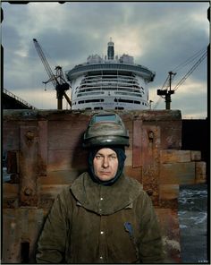 a man wearing a helmet standing in front of a large ship