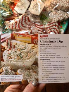 someone holding up a christmas dip recipe in front of candy canes and other treats