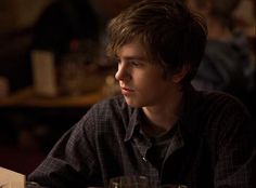 a young man sitting at a table with glasses on it