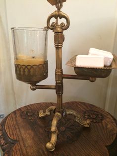 a candle holder on top of a wooden table next to a glass filled with liquid