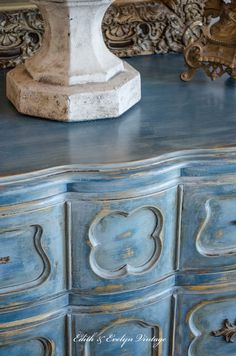 an old dresser with blue paint and ornate carvings on the top, is shown in this image