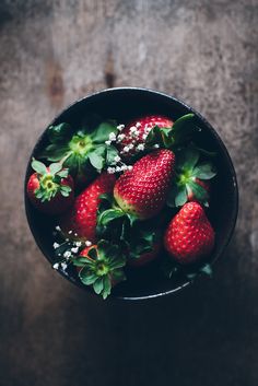 some strawberries are in a bowl on a table