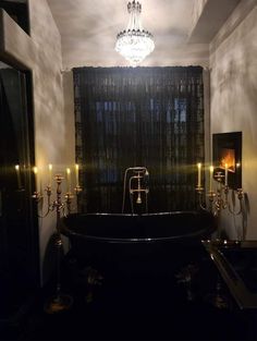 a black bath tub sitting under a chandelier