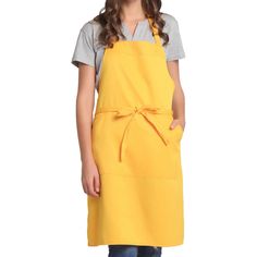 a woman wearing an apron and smiling at the camera with her hands on her hips