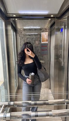 a woman taking a selfie in an elevator with her cell phone up to her ear