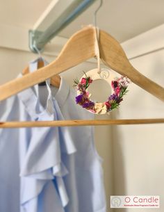 a wooden hanger with a wreath hanging from it's clothes rail next to a blue shirt