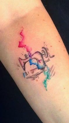 a woman's arm with a tattoo on it that has an elephant and watercolor splash