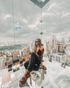 a woman sitting on top of a glass building