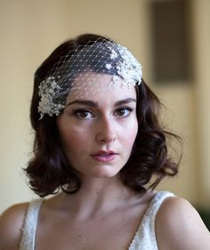 a woman wearing a veil with flowers on it's head is looking at the camera