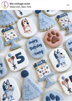 cookies decorated with blue and white icing are arranged in the shape of dogs, balloons, and numbers