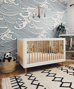 a baby's room with a white crib and blue waves on the wall