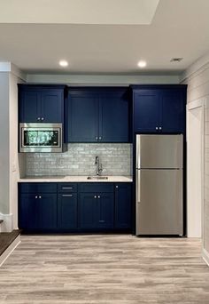 a kitchen with dark blue cabinets and white counter tops is seen in this image from the doorway