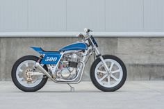 a blue and white motorcycle parked in front of a building with a wall behind it