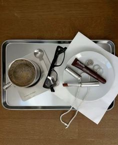 a tray with some items on it including a cup of coffee and eyeglasses