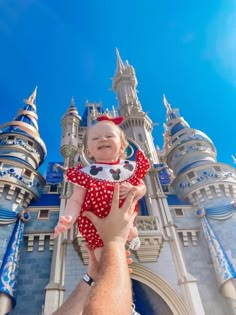 a man holding a baby up to the sky in front of a castle with turrets