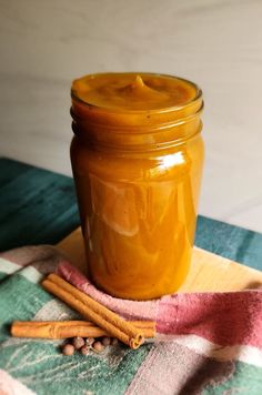 a glass jar filled with liquid sitting on top of a table next to cinnamon sticks