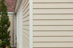 a white fire hydrant sitting on the side of a house