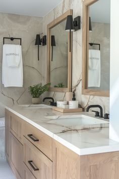 a bathroom with marble counter tops and two mirrors on the wall next to each other