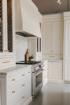 a kitchen with white cabinets and stainless steel stove top oven in the middle of the room