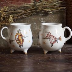 two white mugs sitting on top of a wooden table