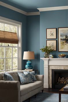 a living room with blue walls and white trim on the fireplace mantel, two couches in front of a fire place