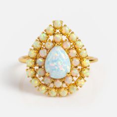 an opalite and gold ring on a white background, with the opatite surrounded by smaller opales