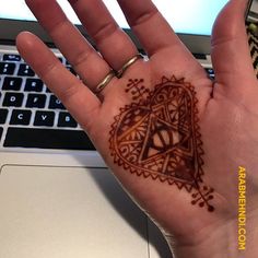 a person's hand with a tattoo on it and a laptop in the background