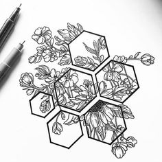 a drawing of some flowers and honeycombs on a sheet of paper next to a pen