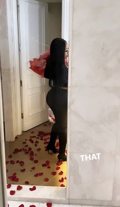 a woman standing in front of a doorway with red rose petals on the floor and walls