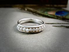 "Delicate fresh water seed pearls are cradled in the folds of this fine silver ring. The pearls are held securely in place by a sterling silver wire. The inside of the ring has been given a dark patina for contrast and to give a more organic look. This ring is under 1/8\" wide and 1/8\" high. This band is lovingly hand crafted by me and looks great alone or with other stack rings. You can choose the option of having the channel where the pearls are set oxidized or bright silver as shown in the l Sterling Silver Pearl Drop Ring For Promise, Sterling Silver Pearl Drop Ring For Promise Occasions, Elegant Sterling Silver Pearl Drop Ring, Silver Ring With Pearl Charm, Dainty Silver Pearl Drop Ring, Sterling Silver Rings With Pearl Drop, Silver Pearl Drop Ring, Silver Pearl Ring With Pearl Drop, Pearl Stacking Ring