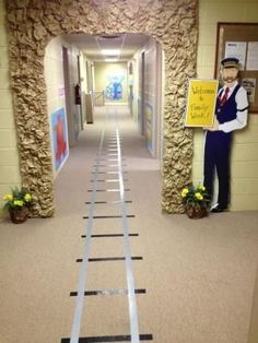 a train track going down the middle of a hallway next to a man in uniform