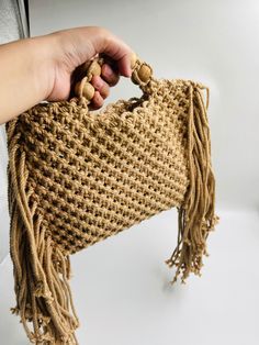 a person is holding a bag made out of jute and wood beads, which are attached to a wall