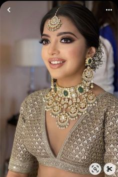 a woman in a bridal outfit with jewelry on her neck and chest, smiling at the camera