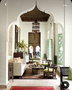 a living room filled with furniture and a chandelier hanging from the ceiling over a doorway