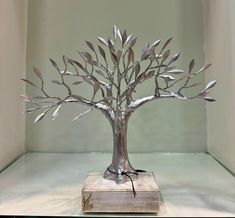 a metal tree sculpture sitting on top of a wooden block