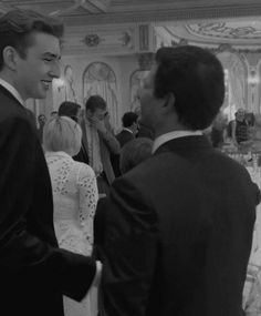 black and white photograph of two men in suits talking to each other at a wedding