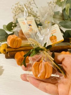 a person holding some kind of candies in their hand with leaves and flowers behind them