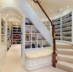 there is a very large closet with many shoes on the shelves and stairs leading up to it