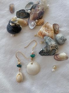 various seashells and pearls are laying on a white sheet, including one with a green bead