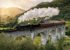 a train traveling over a bridge in the mountains