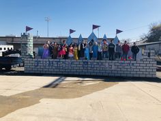 a group of people standing on top of a brick wall in front of a building