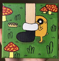 a hand holding up a small painting with mushrooms on it