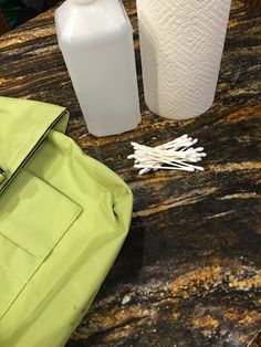 a green bag sitting on top of a table next to a bottle and toilet paper